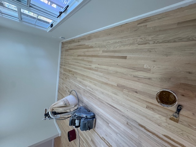 Floor sanding machine working across pale timber boards in an empty room.