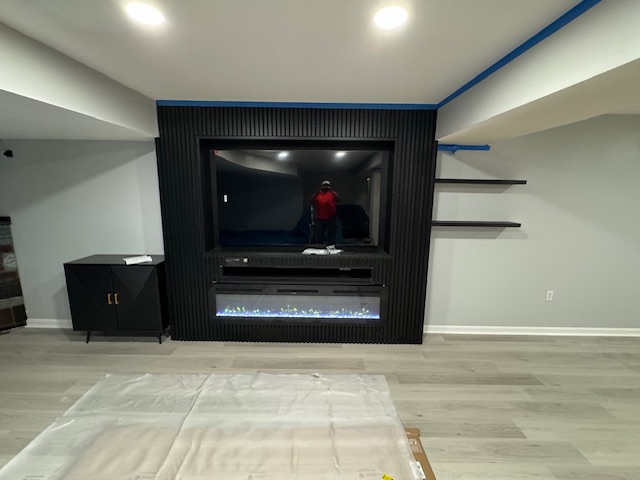 Finished black media and fireplace wall with base cabinets and floating shelves.