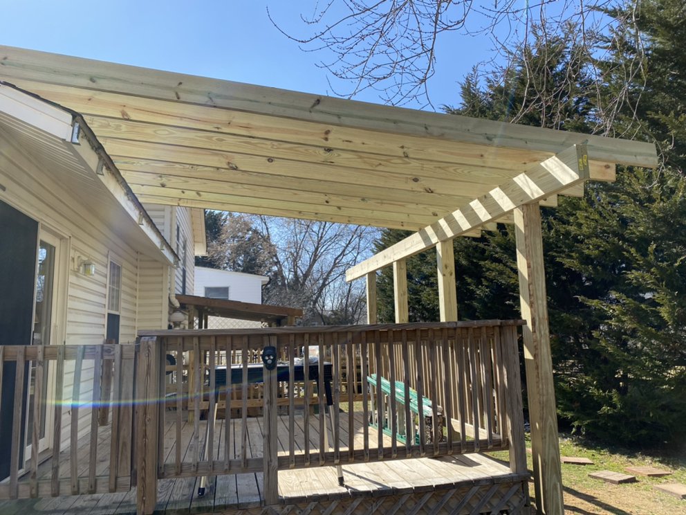 Finished timber pergola built over a deck at the side of a house, with an open slatted roof.